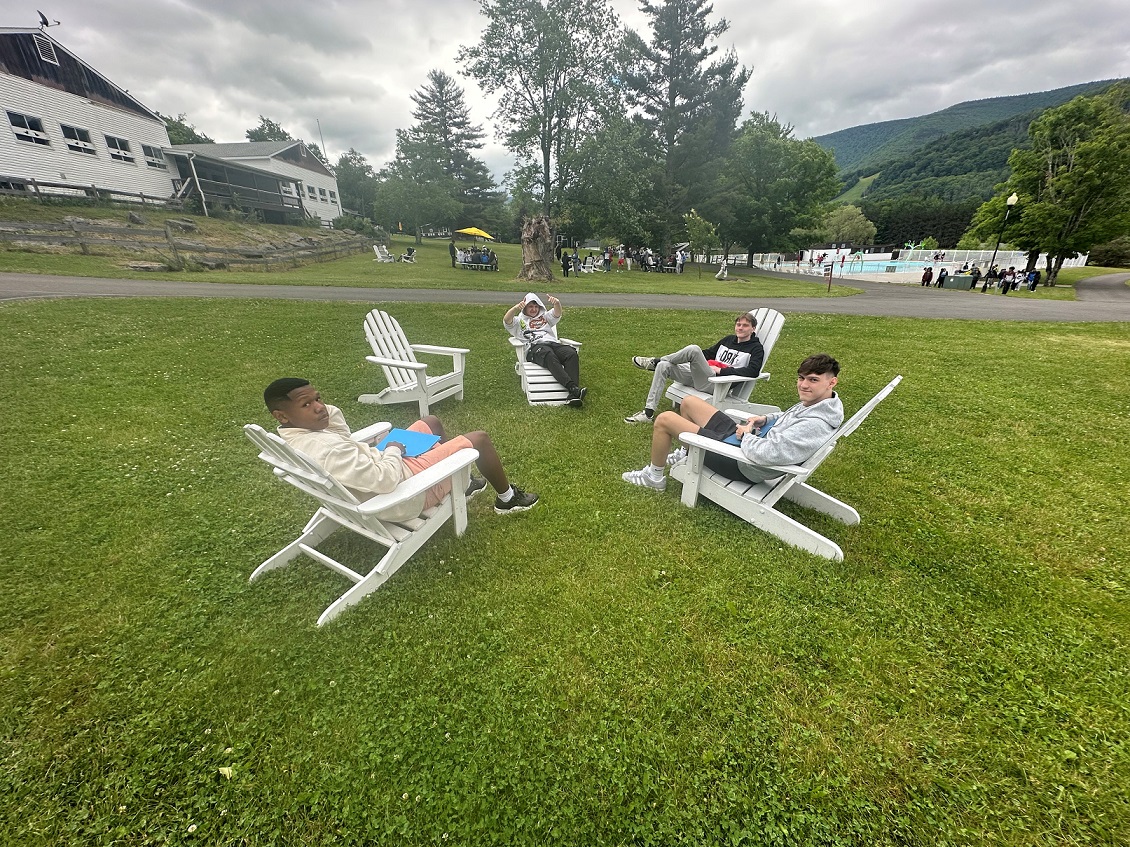 Camp Loyaltown Counselors resting on Adirondack chairs. 
