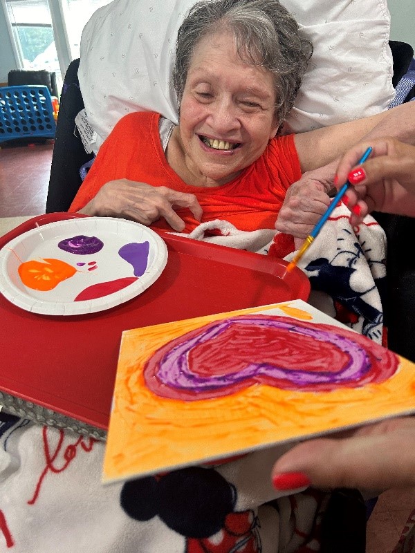 Roz Adler painting a red heart.