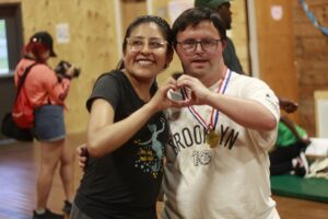 A Camp Loyaltown camper and counselor form a heart with their hands