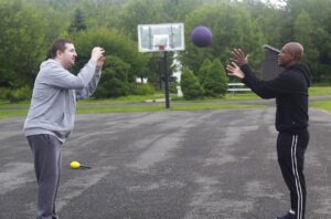 A camper and counselor toss a ball on the basketball court at Camp Loyaltown