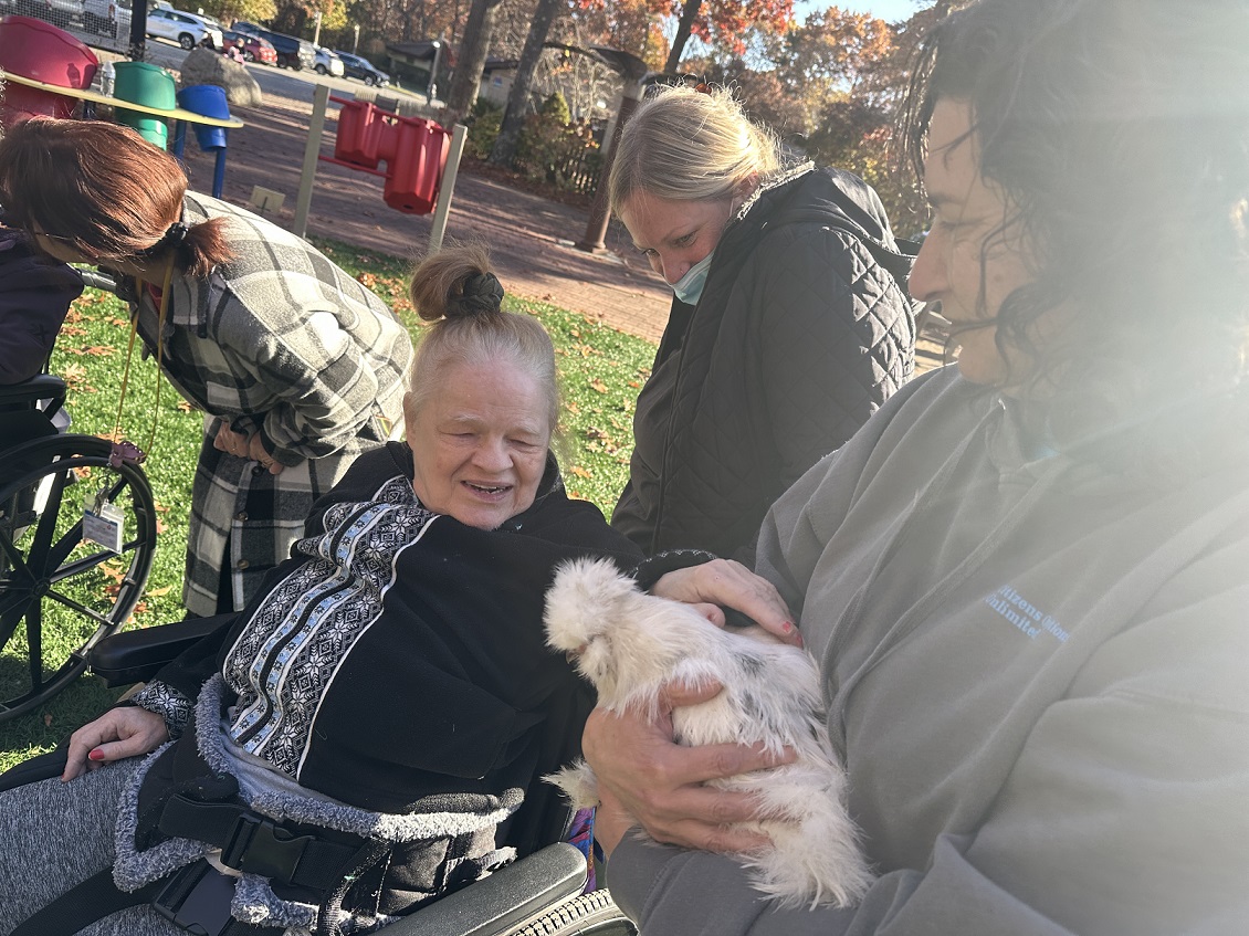A resident of the Shoreham Intermediate Care Facility pets a chicken