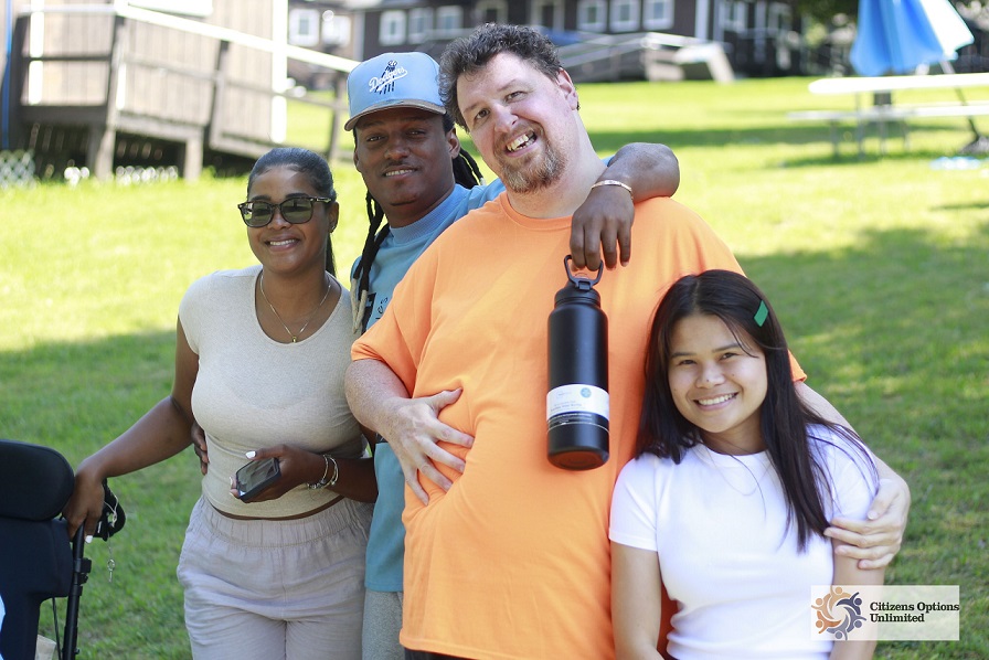Four campers and staff members smiling