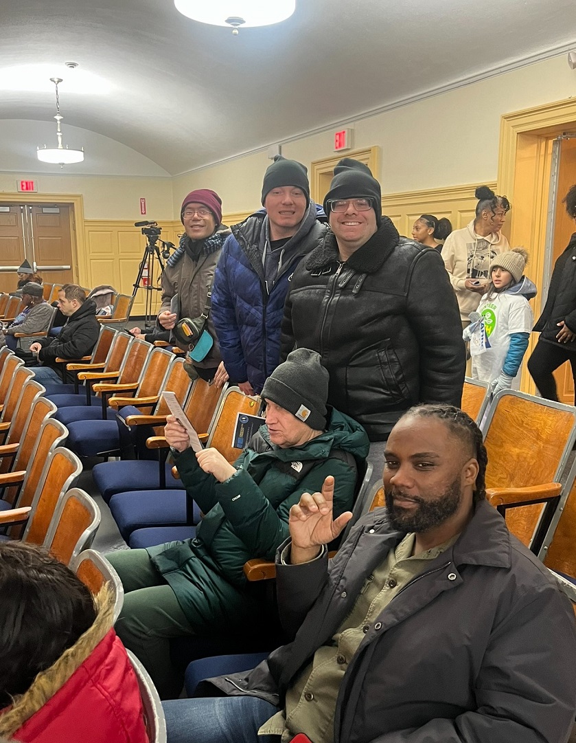 Volunteers and people supported by Citizens Options Unlimited smile in the school auditorium at the event.