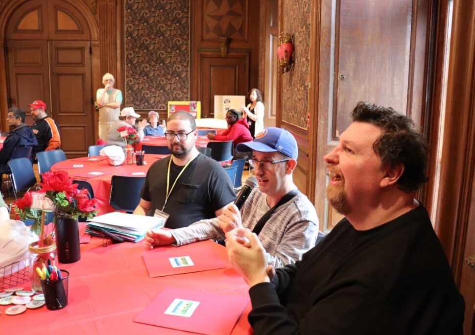 Self-advocates gathered around a table at the Personal Outcome Measures (POMs) Rally.