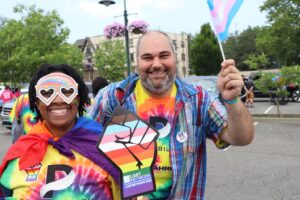 Attendees at the PrideAbility Pride Parade pose for a photo with their sign and flag.