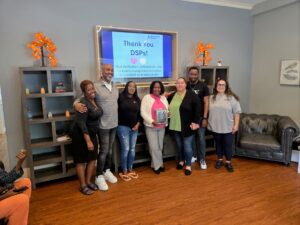 People supported at Red Spring Lane hold up a plaque given to them by Glen Cove nonprofit i Am My Sister for their active participation in the Hope N’ Motion Walk for Youth Mental Health Awareness.