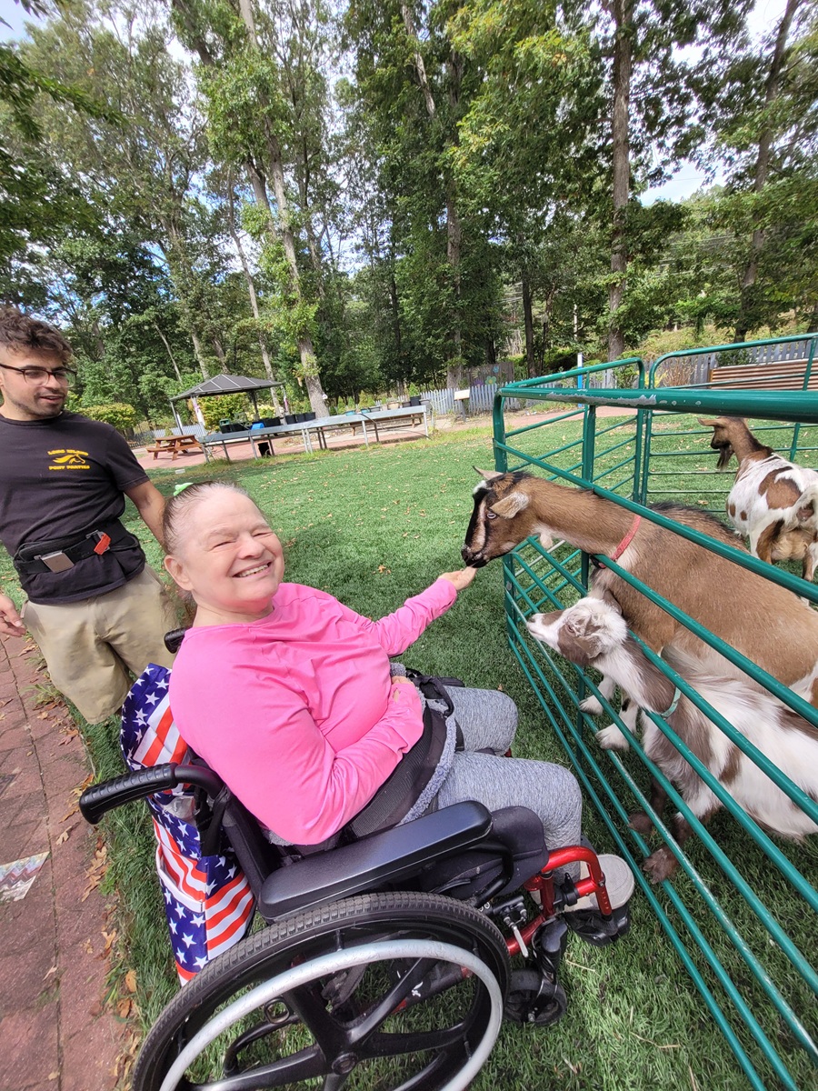 A resident at he Shoreham Intermediate Care Facility feeds a goat at the petting zoo.