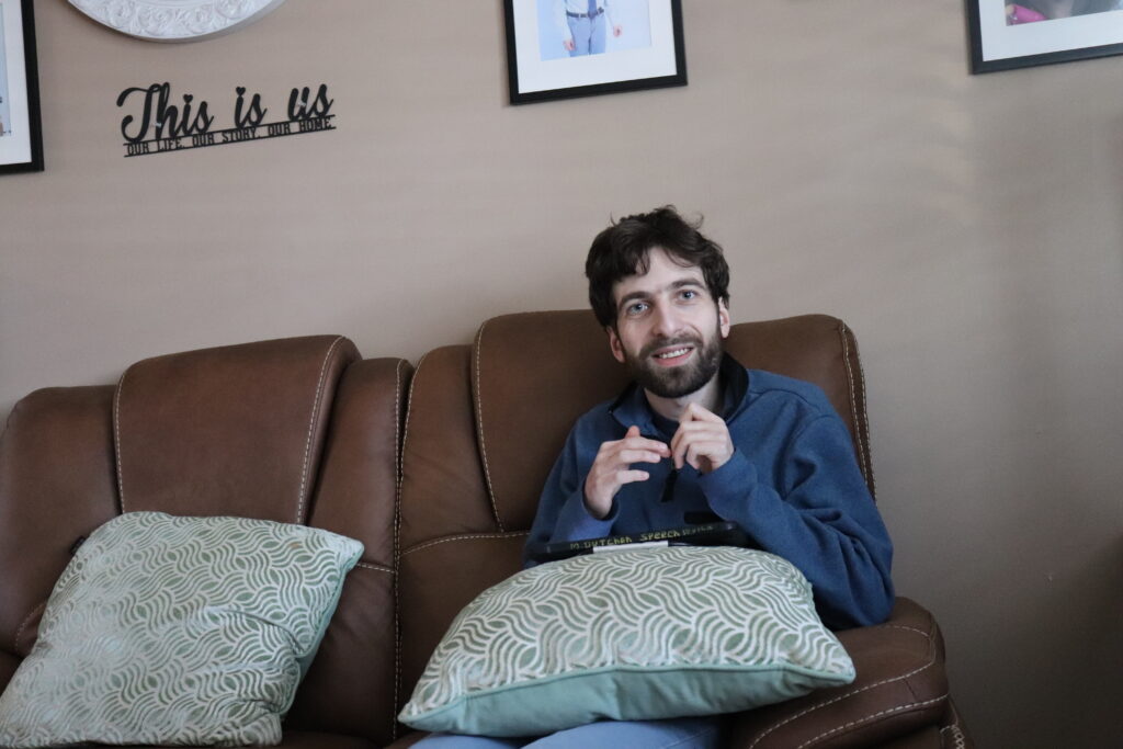 A Citizens Resident sits on the couch in their home.