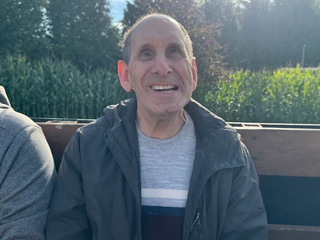 A person supported by Citizens smiles on a bench. 