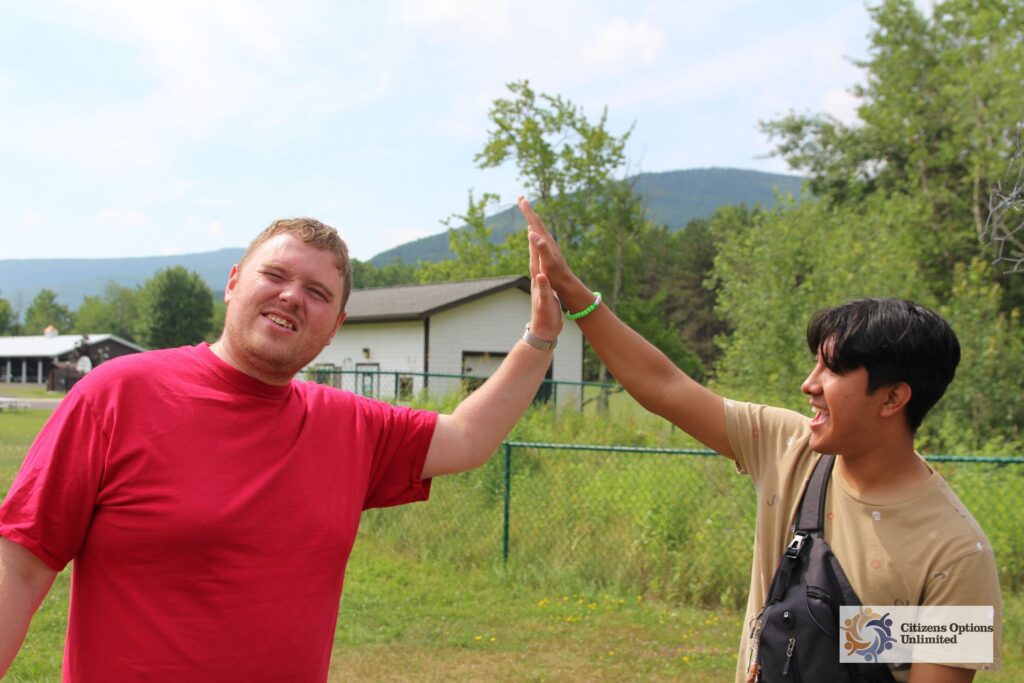 A Camp Loyaltown camper and a counselor high five.