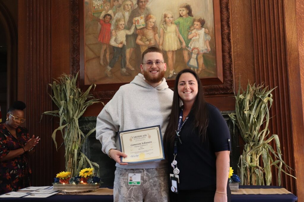 Two Citizens staff members, one who is holding an award he received