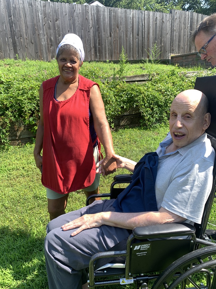 Rose Green holds hand with a person supported by Citizens Options Unlimited in the garden.