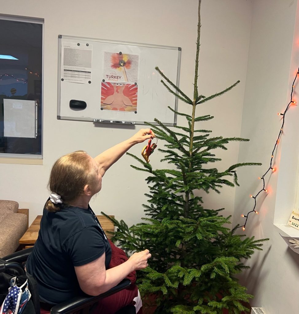Person supported putting ornament on Christmas tree