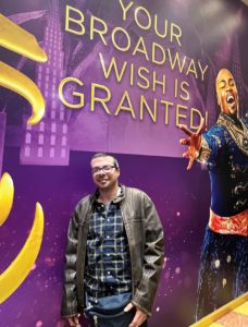 Man poses in front of Aladdin on Broadway