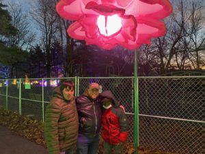 People supported posing in front of flower light art
