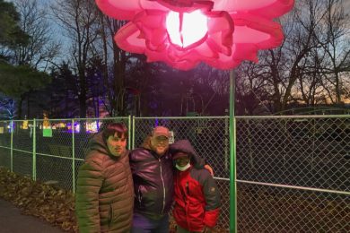 People supported posing in front of flower light art