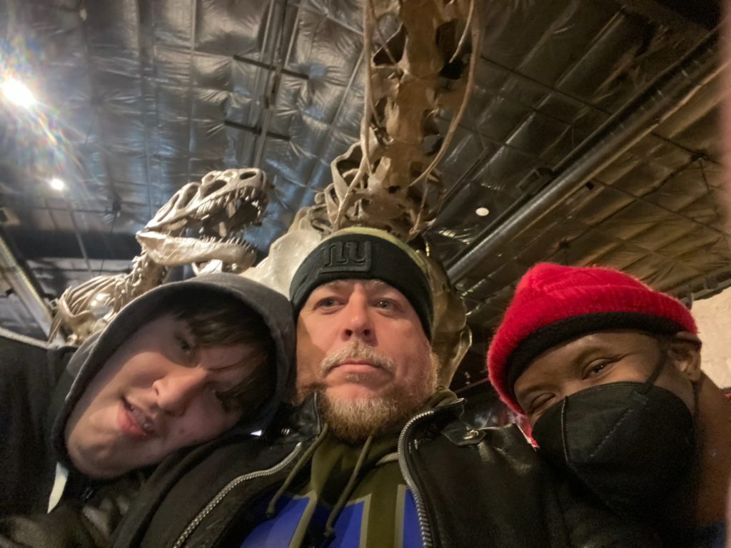 People supported by citizens in front of dinosaur fossil