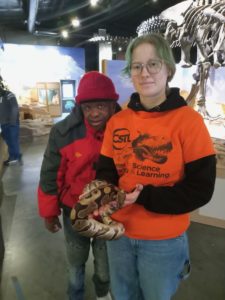 An employee at the dinosaur exhibit shows a snake to a person supported by Citizens