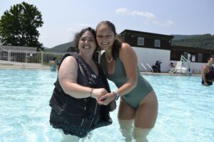 A Camp Loyaltown camper and staff member pose for a photo by the pool