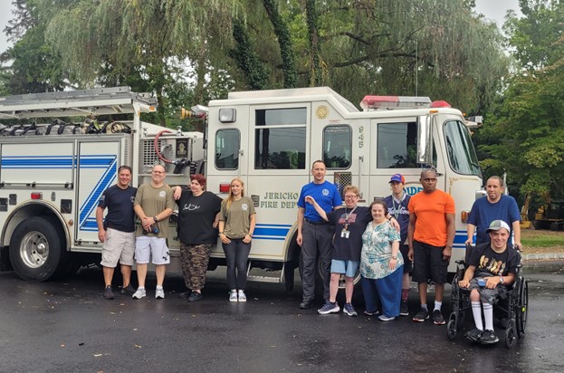 People supported in front of a firetruck after learning about emergency preparedness for Patriot Day.