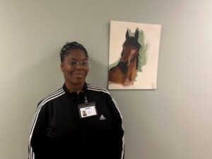 Employee Tamara Morales poses in front of a painting of a horse