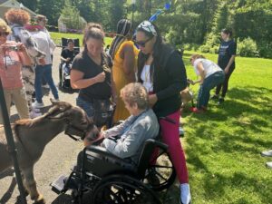 Wilhelmina Waldinger, a resident of Helen Kaplan Center, petting a donkey.