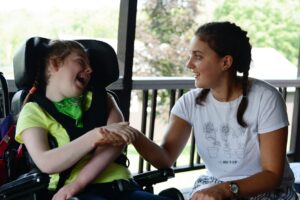 A Camp Loyaltown camper holds hand with a counselor