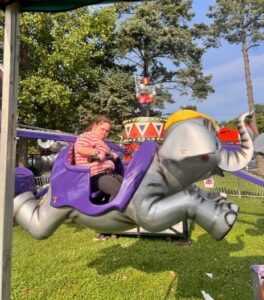 A Pickwick Drive resident rides the Elephant Parade ride at the Lynbrook Titans Carnival