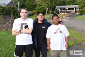 Three campers and staff members pose for a photo outside at Camp Loyaltown
