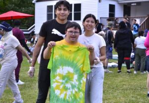 A camper poses for a photo with his newly tie-dyed t-shirt and his counselors