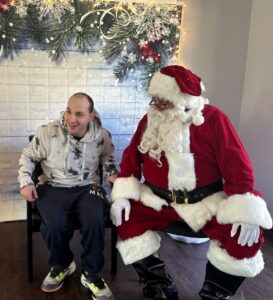 A resident at the Shoreham Intermediate Care Facility sitting next to Santa Claus