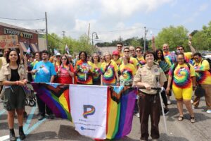 Marchers at the PrideAbility Pride Parade hold a rainbow and various pride flags.