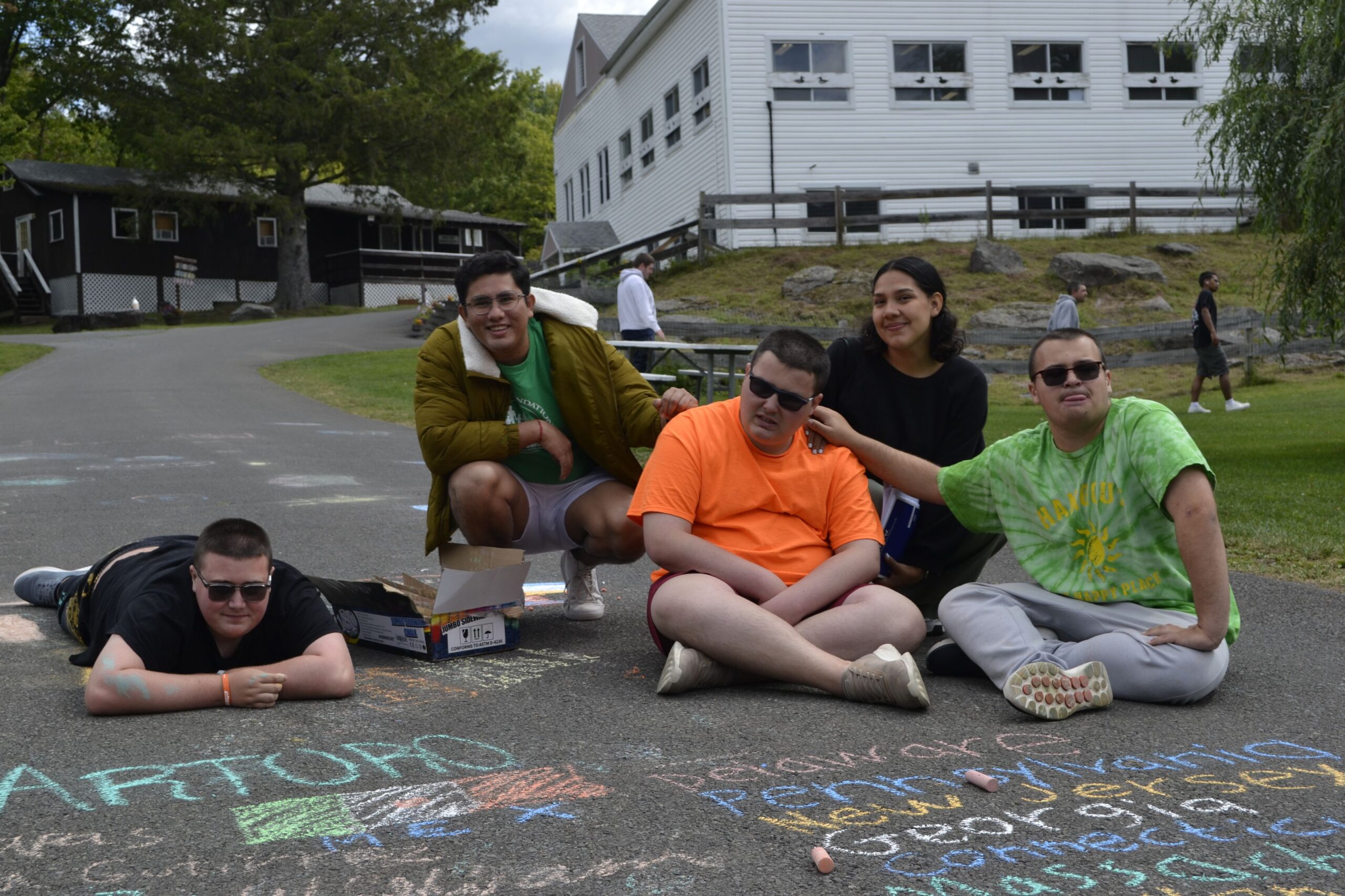 Camp Loyaltown campers draw with chalk on the pavement.