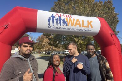 Four people supported by and staff members of Citizens in front of the AHRC Foundation Walk arch.