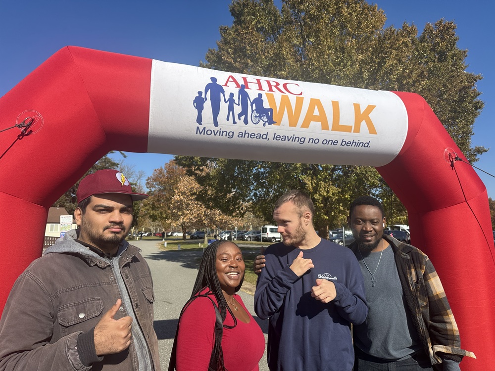 Four people supported by and staff members of Citizens in front of the AHRC Foundation Walk arch.